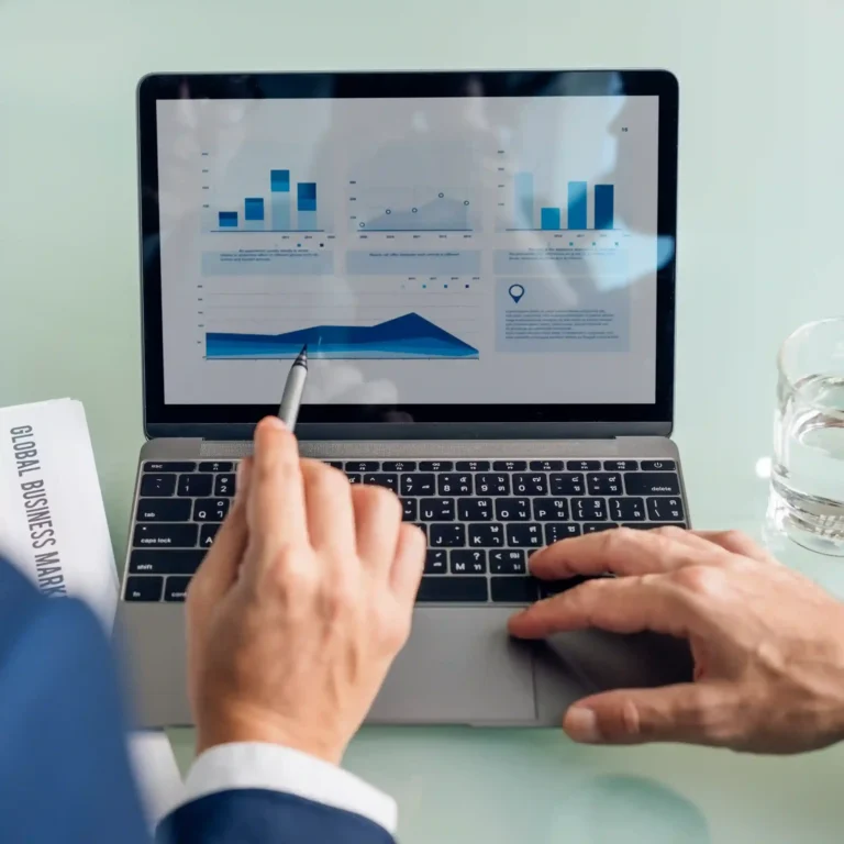 A close-up of a professional using a stylus to point at detailed financial growth charts on a laptop screen. Kloudac, a premier accounting firm in Dubai, prioritizes precision in all accounting services to ensure 100% reporting accuracy for our clients.