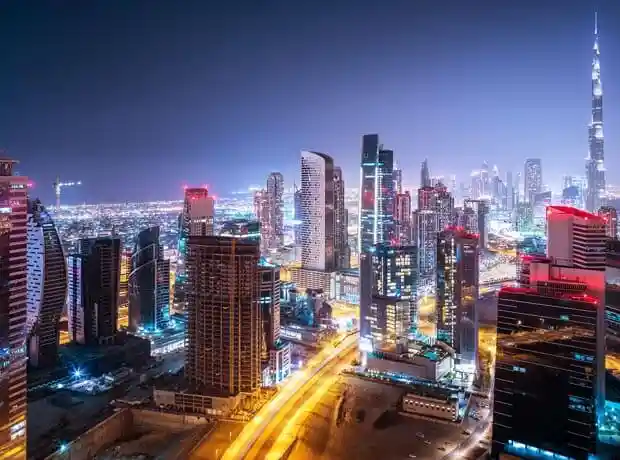 Aerial view of the dazzling Dubai skyline at night with numerous illuminated skyscrapers and the Burj Khalifa, illustrating the dynamic environment for Kloudac's Business Setup in Dubai and Accounting Firm in Dubai services.