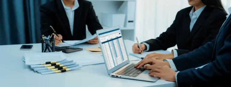 Professional team meeting provided by a top accounting firm in Dubai. Consultants are reviewing detailed financial data and spreadsheets on a laptop as part of comprehensive accounting services in Dubai.