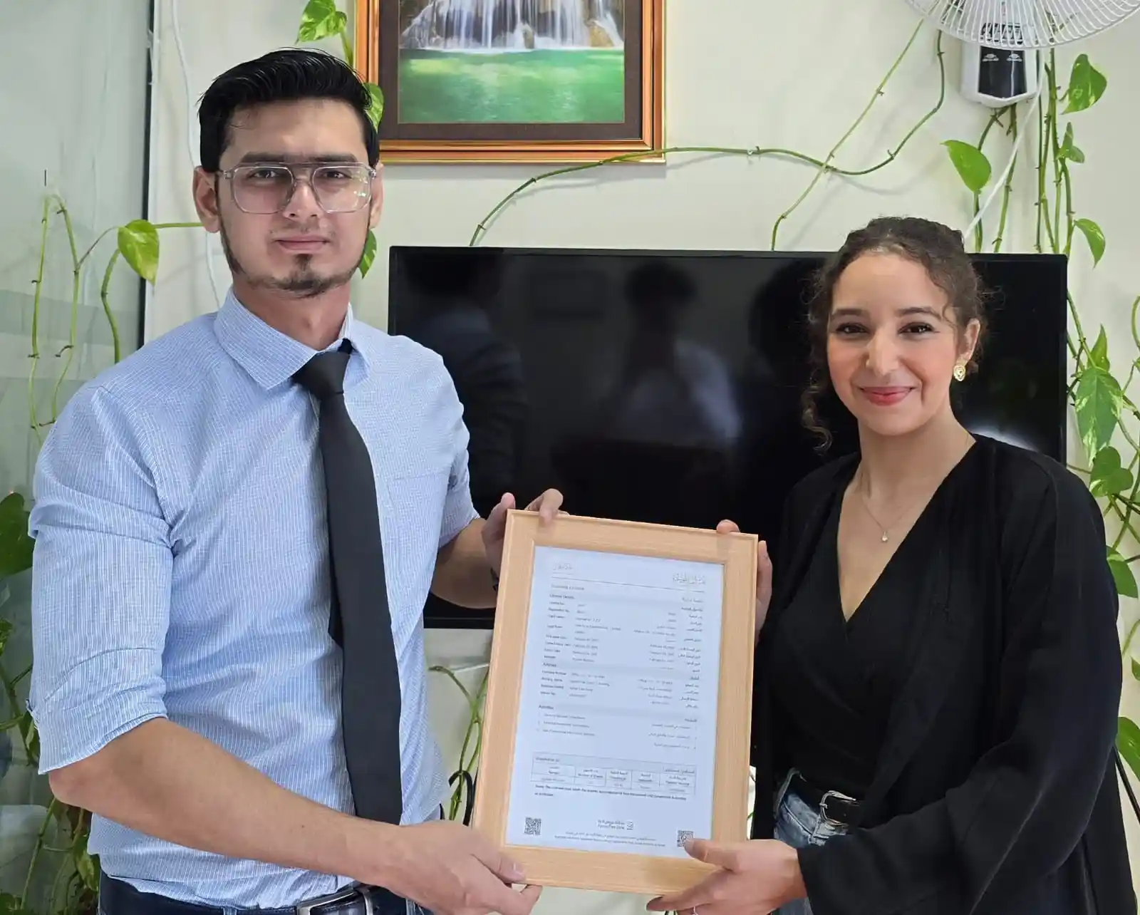 A professional man and woman holding a framed business license, showcasing a successful business setup in Dubai facilitated by Kloudac. As a premier Accounting firm, Kloudac provides expert Accounting Services to help new entrepreneurs establish and grow their ventures in Dubai.