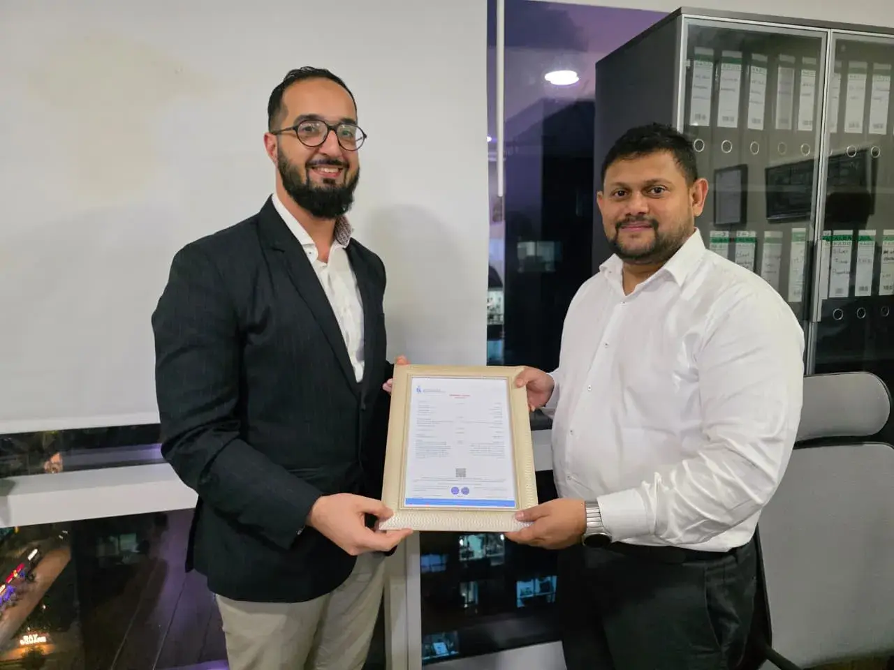 A professional consultant from Kloudac, a premier Accounting firm, presenting a framed business license to a successful client in a modern office. This milestone represents a seamless business setup in Dubai supported by the dedicated Accounting Services offered by the Kloudac team.
